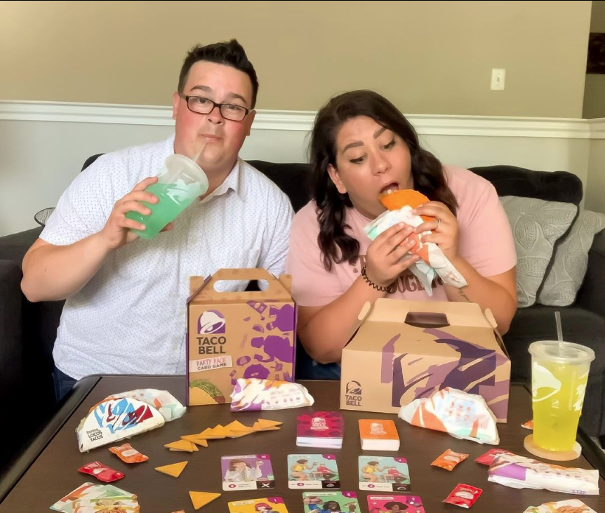 Tyler and McKenzie, from Those Broke Gamers, eating Taco Bell and playing the Taco Bell Party Pack card game.